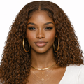 Woman with long, curly brown hair wearing gold hoop earrings and necklaces on a white background